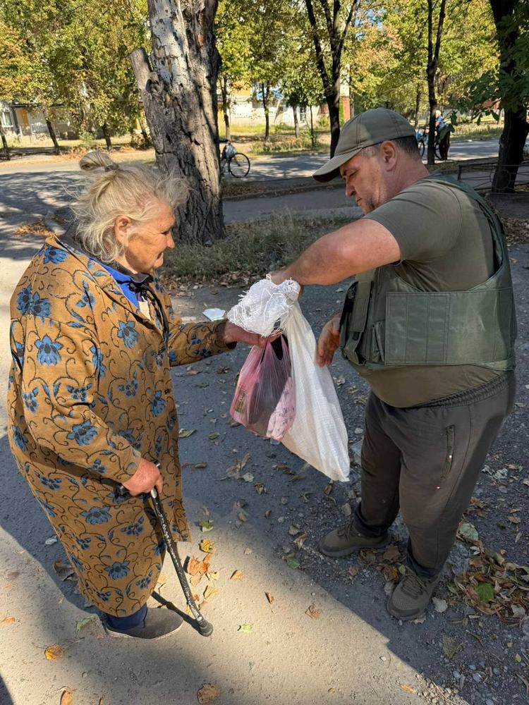 A volunteer handing food parcels to an elderly resident